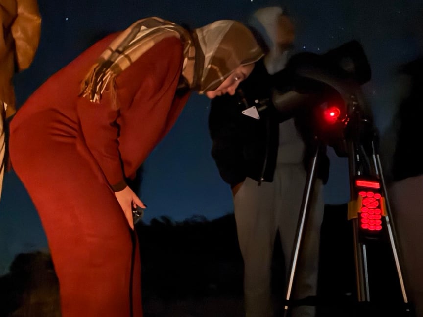 Visitante observando o céu por um telescópio durante o Tour Astronômico na Serra da Canastra