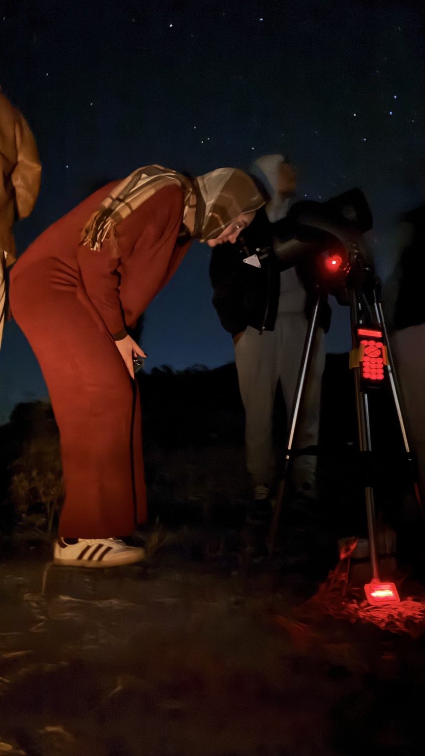 Visitante observando o céu por um telescópio durante a noite